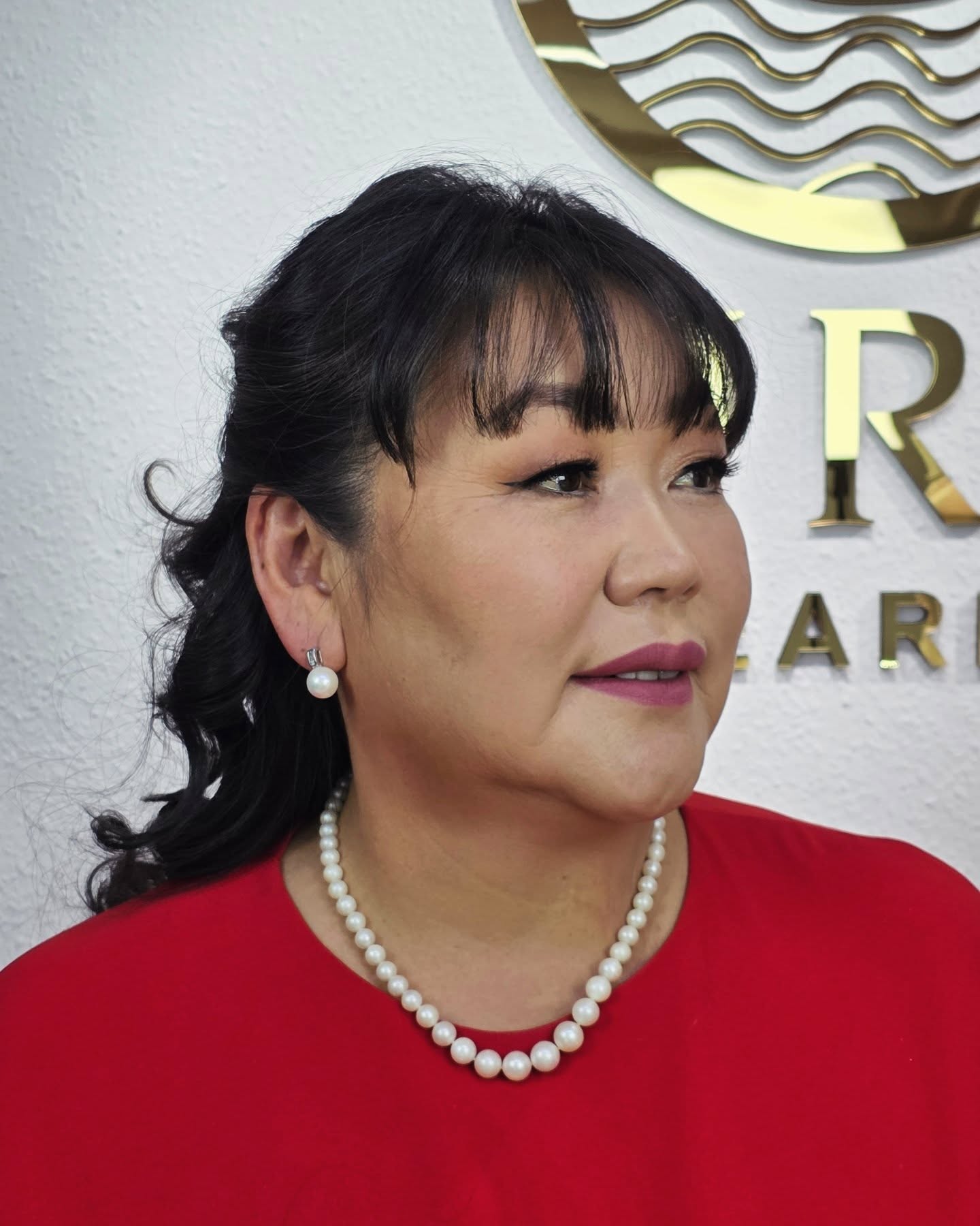 Sophisticated woman in red wearing a short classic white pearl necklace and matching earrings from Murun Pearls