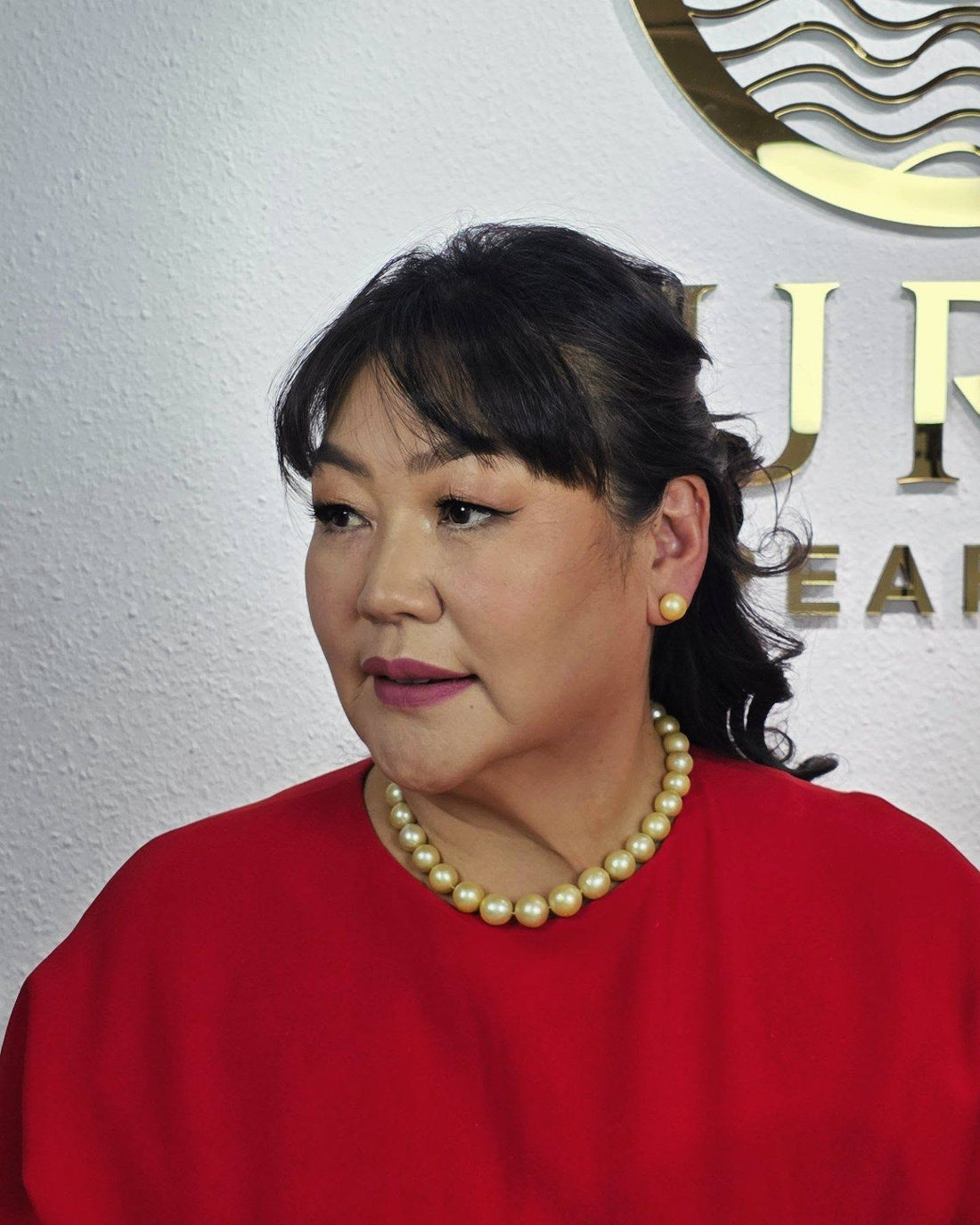 Elegant woman wearing a golden South Sea pearl necklace and matching stud earrings by Murun Pearls