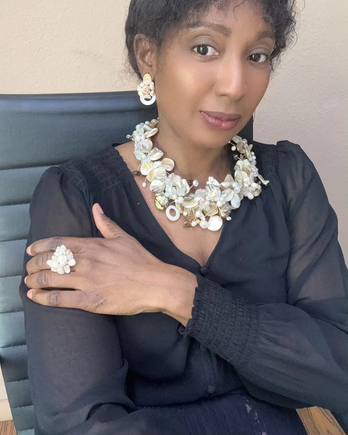 Elegant woman wearing handcrafted Murun Pearls floral necklace set with golden petals, freshwater pearls, and shell accents, paired with matching earrings and statement ring.